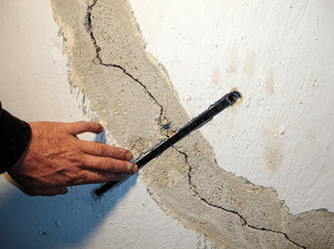 A wall with a large crack is being inspected by a professional in Cape Coral, FL